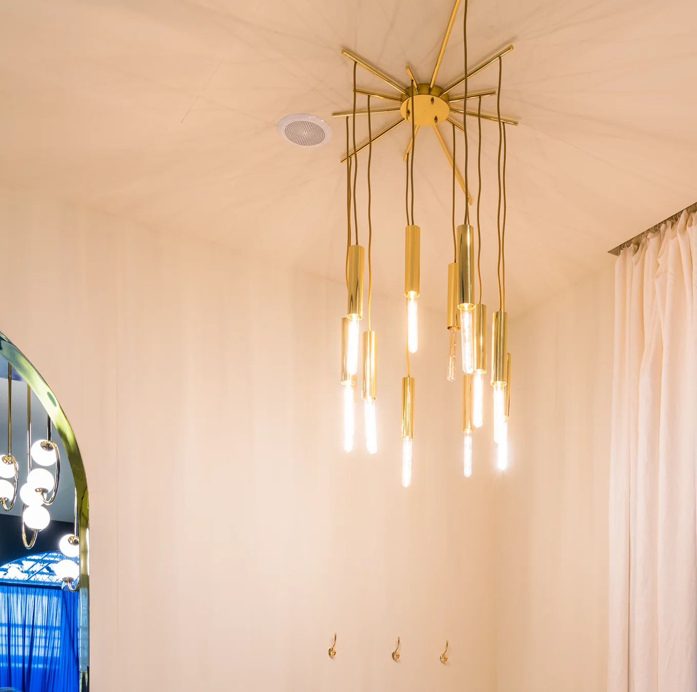 Lightrain Ceiling Lamp with sculptural brass structure, suspended cylinders, and elegant filament bulbs, creating a warm and artistic illumination for luxury interiors.