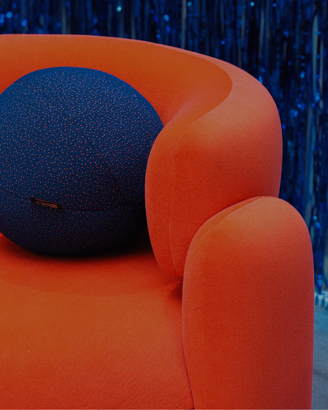 Fully upholstered armchair with rounded backrest, bold geometric curves, and three upholstered legs, elevating modern interiors with elegance and unique style