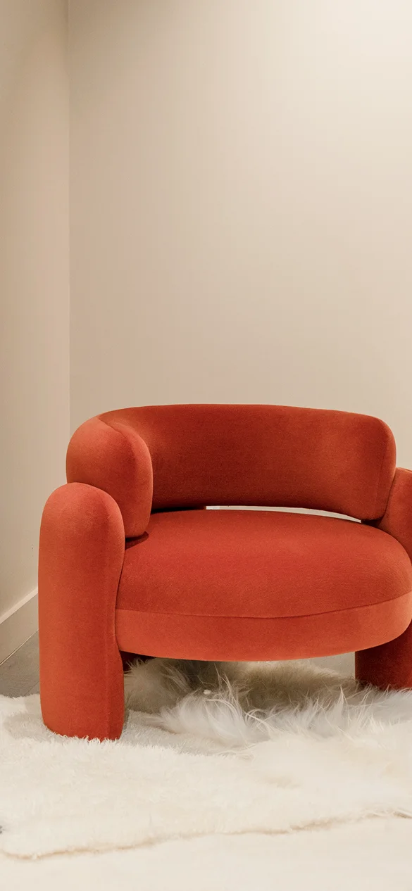 Fully upholstered armchair with rounded backrest, bold geometric curves, and three upholstered legs, elevating modern interiors with elegance and unique style