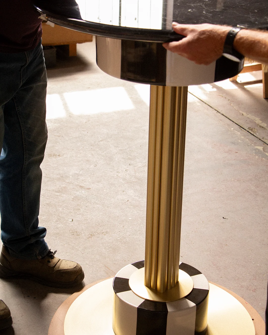 Detailed view of the structural joint and brushed brass backbone of a MAAM collection table, highlighting the stability and study of the assembly.